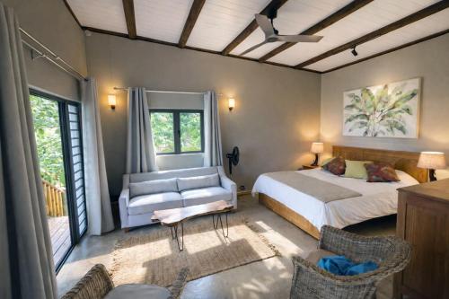 a bedroom with a bed and a couch and chairs at Terganic Farmstay in Grand Sable
