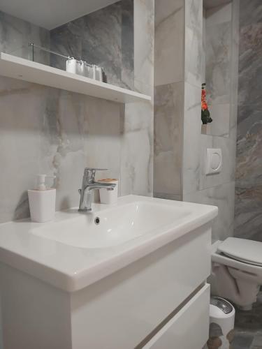 a white bathroom with a sink and a toilet at Apartman Herceg in Ljubuški