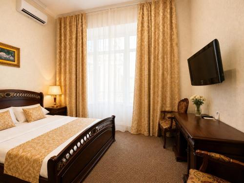 a hotel room with a bed and a desk and a television at Oreanda Hotel in Odesa