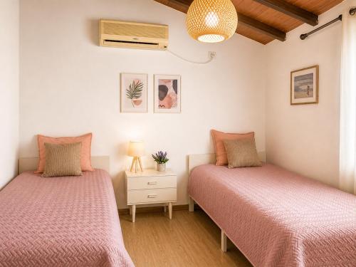 two beds in a bedroom with pink sheets at Oropos Cozy House in Néa Palátia