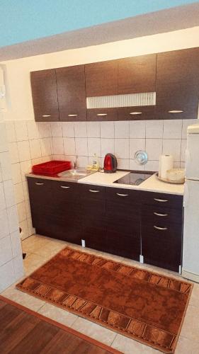 a kitchen with black cabinets and a white refrigerator at Apartman Orijent in Kulen Vakuf