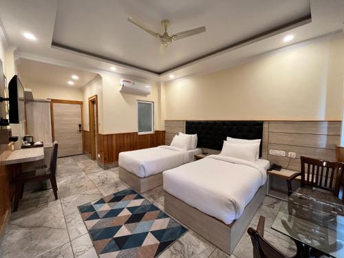 a hotel room with two beds and a desk at Nomadic Inn in Dharamshala