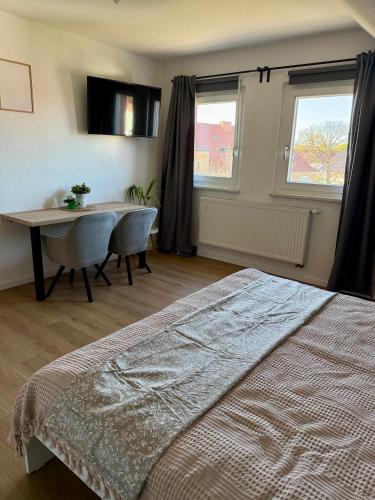 a bedroom with a bed and a table and two windows at Ferienwohnung Carla in Weißensee