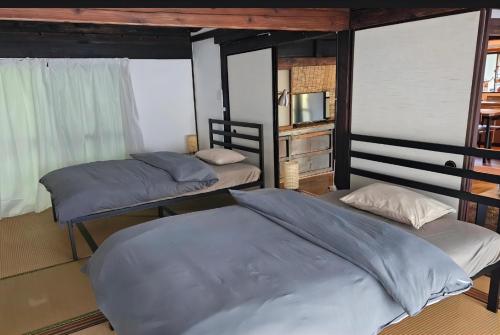 two beds in a room with two windows at 花子のいえ hanako's house in Amidaji
