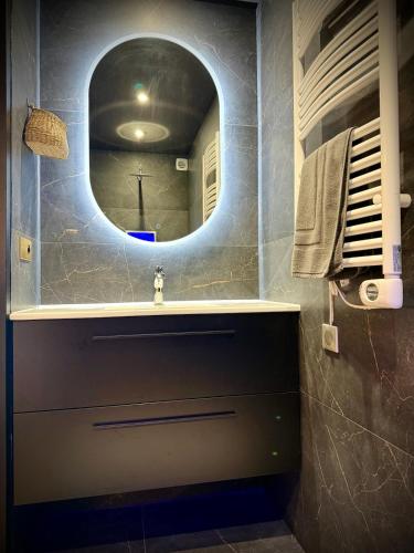 a bathroom with a sink and a round mirror at Elegance Bretonne in Pléneuf-Val-André