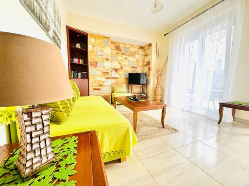 a living room with a yellow bed and a stone wall at Holiday Dream Thalia Apartment in Mastihari