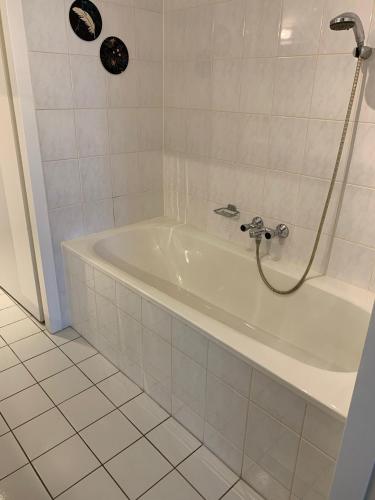 a white bath tub with a shower in a bathroom at Appartement Zuiderzeestate Makkum in Makkum