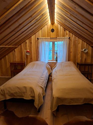 two beds in a wooden room with a window at Stastugan in Grönhult
