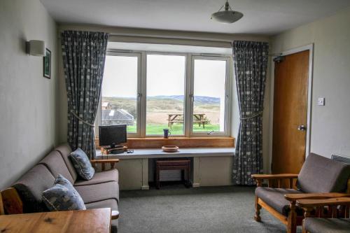 a living room with a couch and a desk in front of a window at Scoor House - Laggan in Bunessan