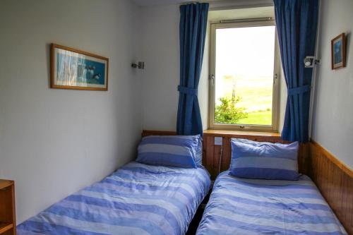 two beds in a room with a window at Scoor House - Laggan in Bunessan