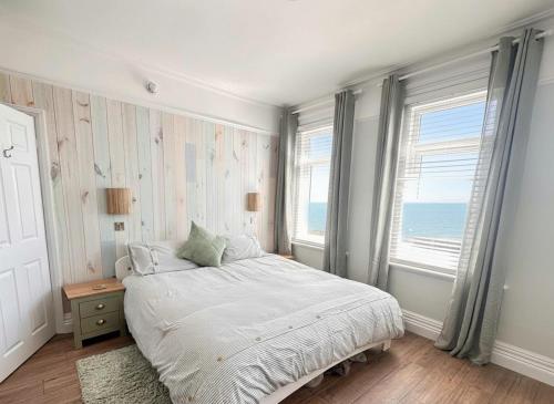 a bedroom with a bed and two windows at Exmouth Devon Luxurious Flat OverlookingThe Sea in Exmouth