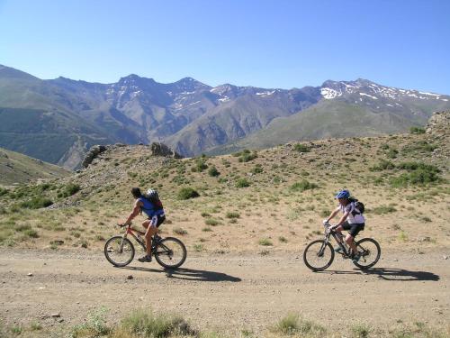 two people riding bikes on a dirt road in the mountains at Hotel Rural Huerta del Laurel in Monachil