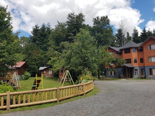 a yard with a wooden fence and a playground at Cabañas Santa Maria Pucon in Pucón