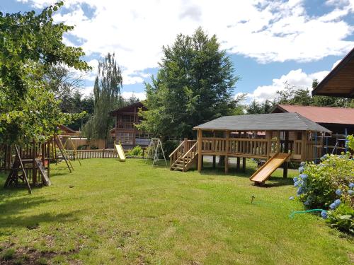 a playground in a yard with wooden play equipment at Cabañas Santa Maria Pucon in Pucón