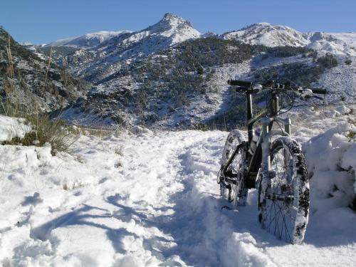 a bike parked in the snow with mountains in the background at Hotel Rural Huerta del Laurel in Monachil