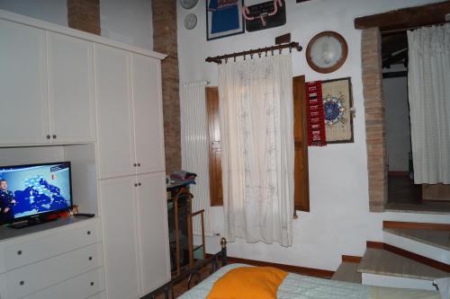 a living room with a tv and white cabinets at Il Pozzo Della Citerna in Castelnuovo Berardenga