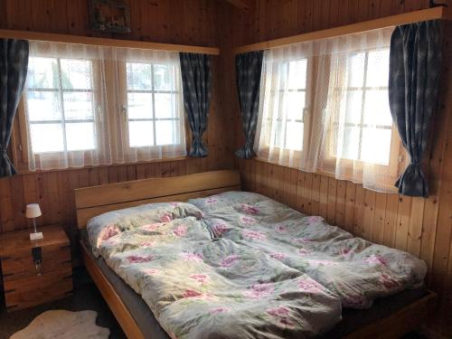 a bedroom with a bed in a room with windows at Chalet Alpen Charme in Turtmann