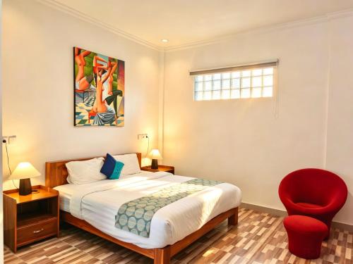 a bedroom with a bed and a red chair at Brady's B&B Close To Sanur Beach in Sanur