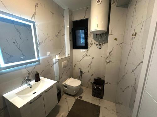 a bathroom with a sink and a toilet and a window at Dali Apartment in Bar