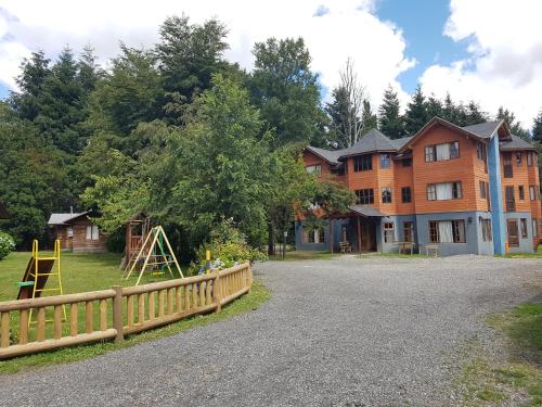 a house with a wooden fence and a playground at Cabañas Santa Maria Pucon in Pucón
