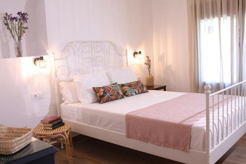 a white bedroom with a white bed and a window at Casa Rural La Canaleja in Berrocalejo