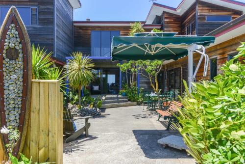 un patio con sillas, sombrilla y plantas en Absolute Beachfront B&B, en Napier