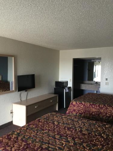 a hotel room with two beds and a flat screen tv at Country Inn Motel in Waukomis