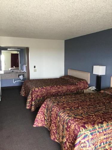 a hotel room with two beds and a lamp at Country Inn Motel in Waukomis
