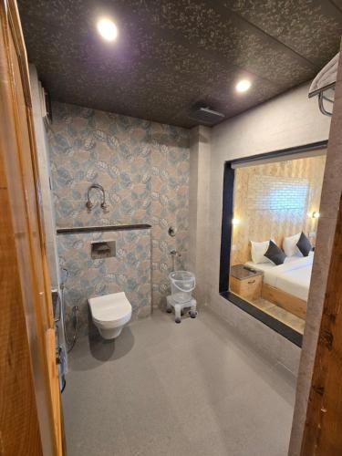 a bathroom with a toilet and a bed in a room at The Park Green Resorts in Manāli