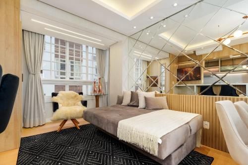 a bedroom with a large bed and a chair at Apto bem no Centro 2 dorm by Achei Gramado in Gramado