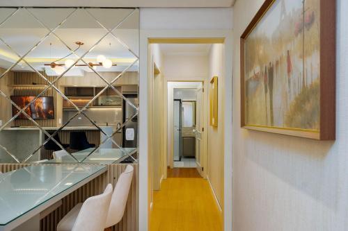 a hallway with a glass counter and white chairs at Apto bem no Centro 2 dorm by Achei Gramado in Gramado