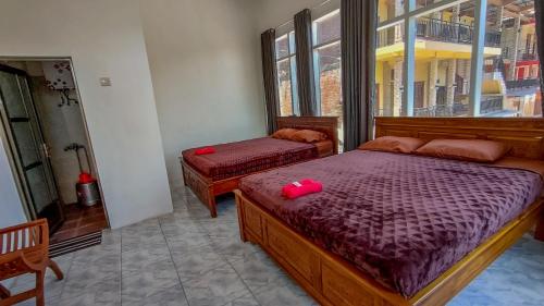a bedroom with two beds and a window at Hotel Nur Cahaya - Syariah in Probolinggo
