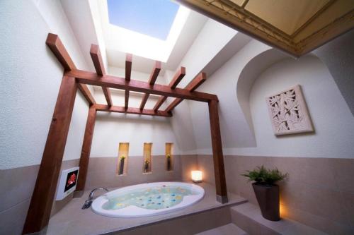 a bathroom with a large bath tub with a skylight at ホテル クレア in Hasuda