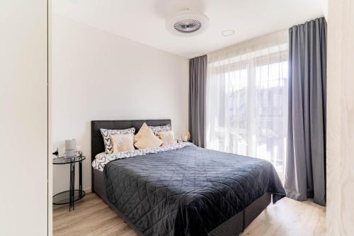 a bedroom with a bed and a large window at Skylum 17th Floor Apartment in Vilnius