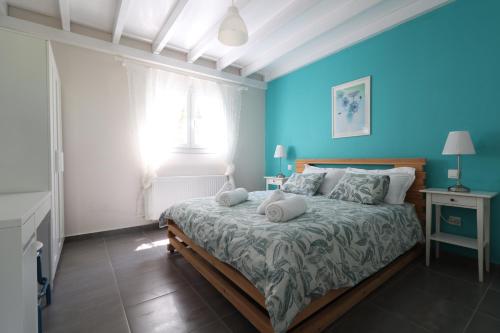a bedroom with a bed with blue walls and a window at Corfu Green Escape in Achílleion