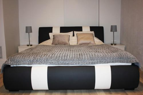 a bedroom with a black and white bed with two lamps at Sky Apartments Riga in Riga