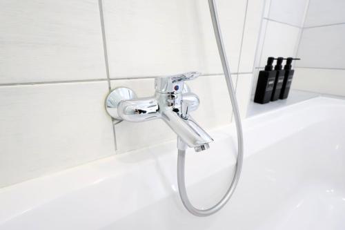 a shower head in a white tiled bathroom at Appartementhaus Ludwig in Mörbisch am See