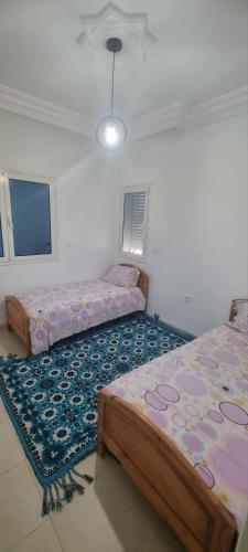 a bedroom with two beds and a rug at Maison à louer in Chebba