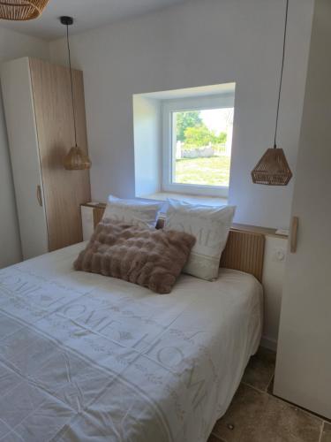 a bedroom with a bed with white sheets and a window at La P'tite Pierre in Ineuil