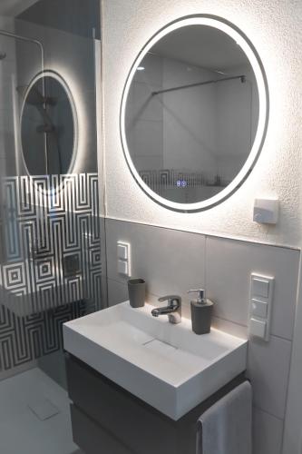 ein Badezimmer mit einem weißen Waschbecken und einem Spiegel in der Unterkunft Ferienwohnung Ullrichshof Oberlausitz - Sauna Grillplatz Panoramablick in Malschwitz