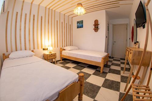 two beds in a room with a checkered floor at Bohem Pansiyon in Kuşadası