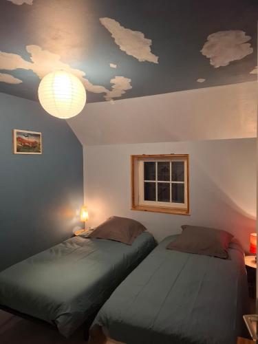 two beds in a room with clouds painted on the ceiling at Kazh bihan in Guissény