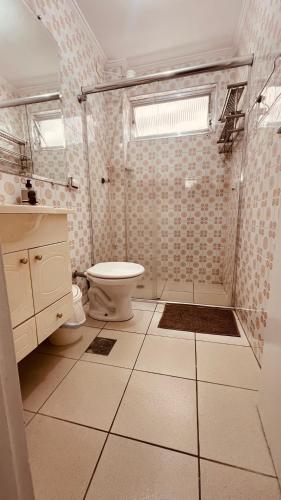 a bathroom with a toilet and a glass shower at Espaço tranquilo e de lazer em Guarujá in Guarujá