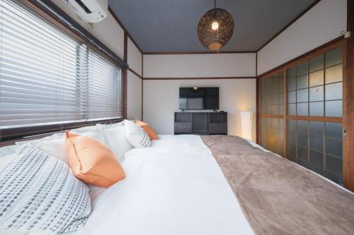 a bedroom with a large white bed and a television at KEI HOUSE Yamato 201 in Yamato