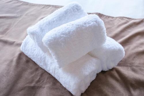 a white towel on top of a bed at KEI HOUSE Yamato 201 in Yamato