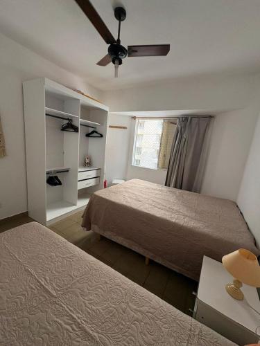 a bedroom with two beds and a ceiling fan at Espaço tranquilo e de lazer em Guarujá in Guarujá