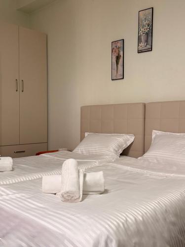 a bedroom with two beds with white sheets and towels at Bloom House Përmet in Përmet
