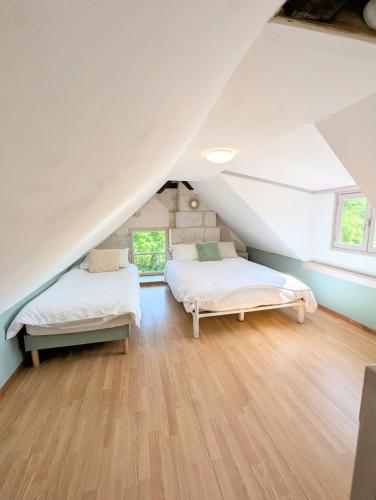 two beds in a attic bedroom with wooden floors at Cottage de charme en pleine nature avec piscine in Saint-Philbert-du-Peuple