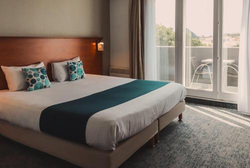 a bedroom with a large bed with a large window at The Originals Boutique, Hôtel Admiral's, Les Sables-d'Olonne in Les Sables-d'Olonne