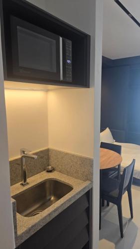 a kitchen with a sink and a microwave and a table at Porto2life Máximo 6 pessoas in Porto De Galinhas